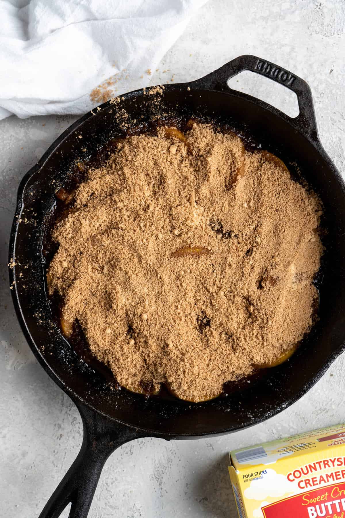 Brown sugar and cinnamon spread on top of peaches in a cast iron skillet