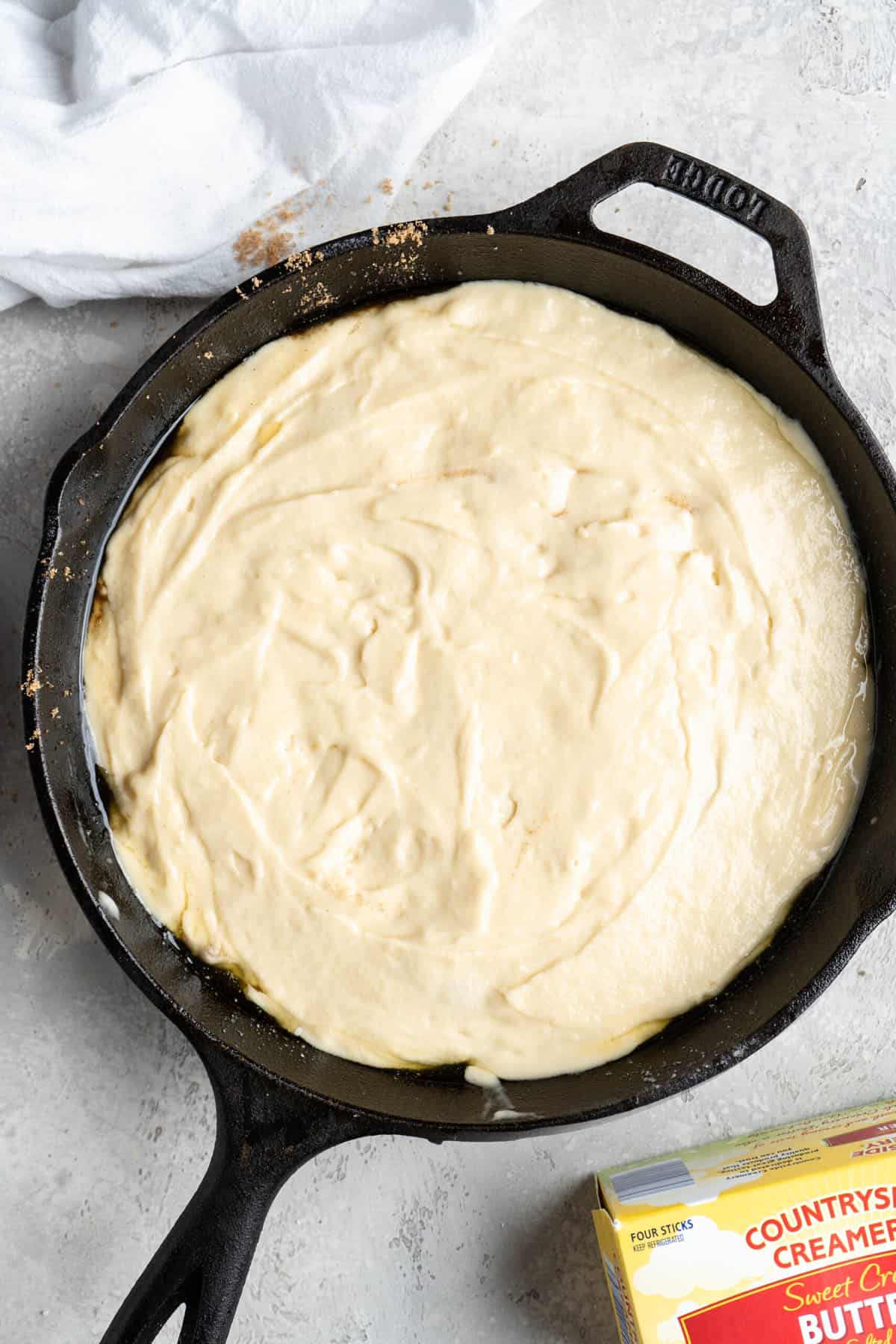 Cake batter spread in a cast iron skillet