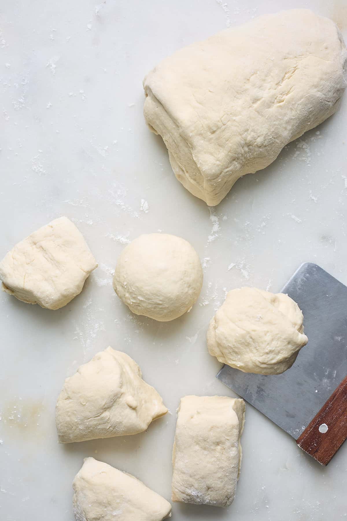 A bench scraper cutting dough into balls