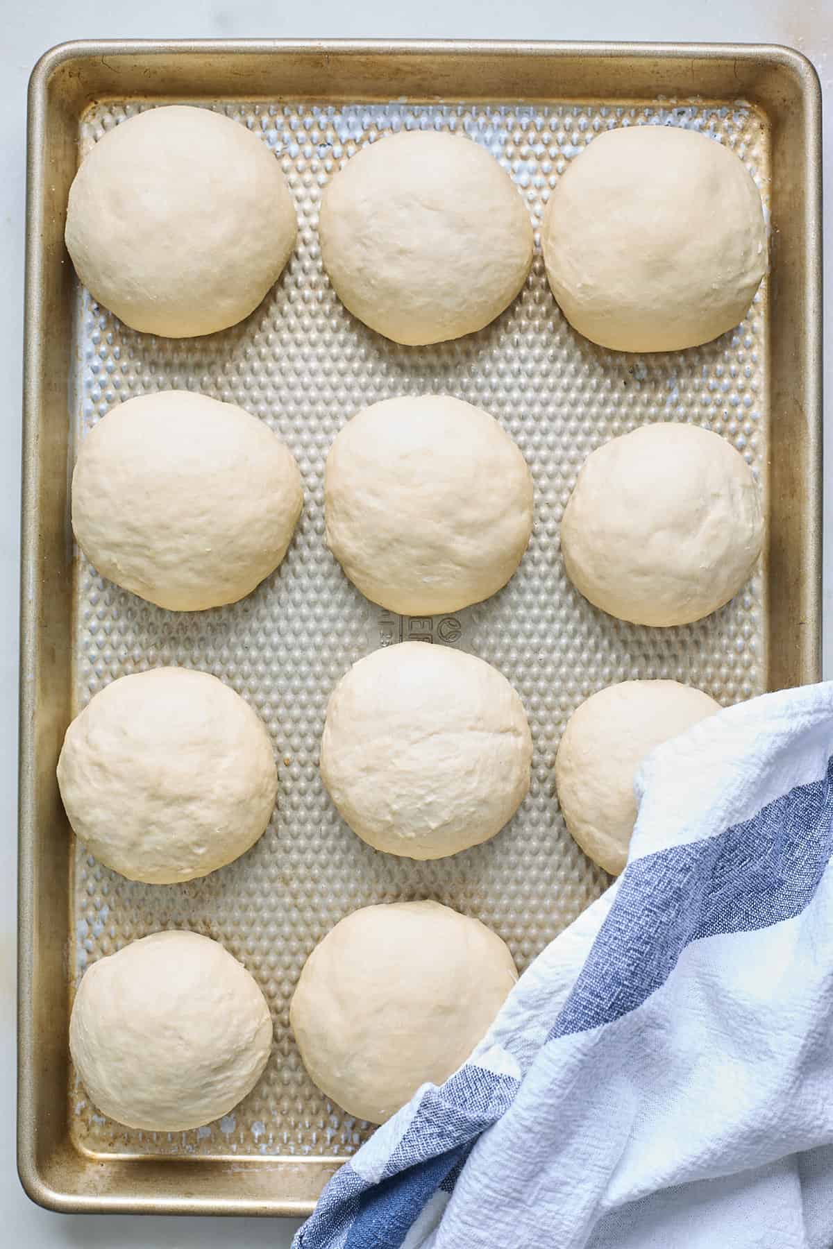 Dough balls in a baking pan before covering with a towel