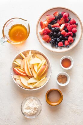 Fresh berries and apple slices along with spices in separate bowls
