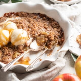 An apple brown betty being served with two spoons scooping some out