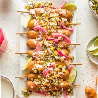 Elote corn dogs on a white serving platter