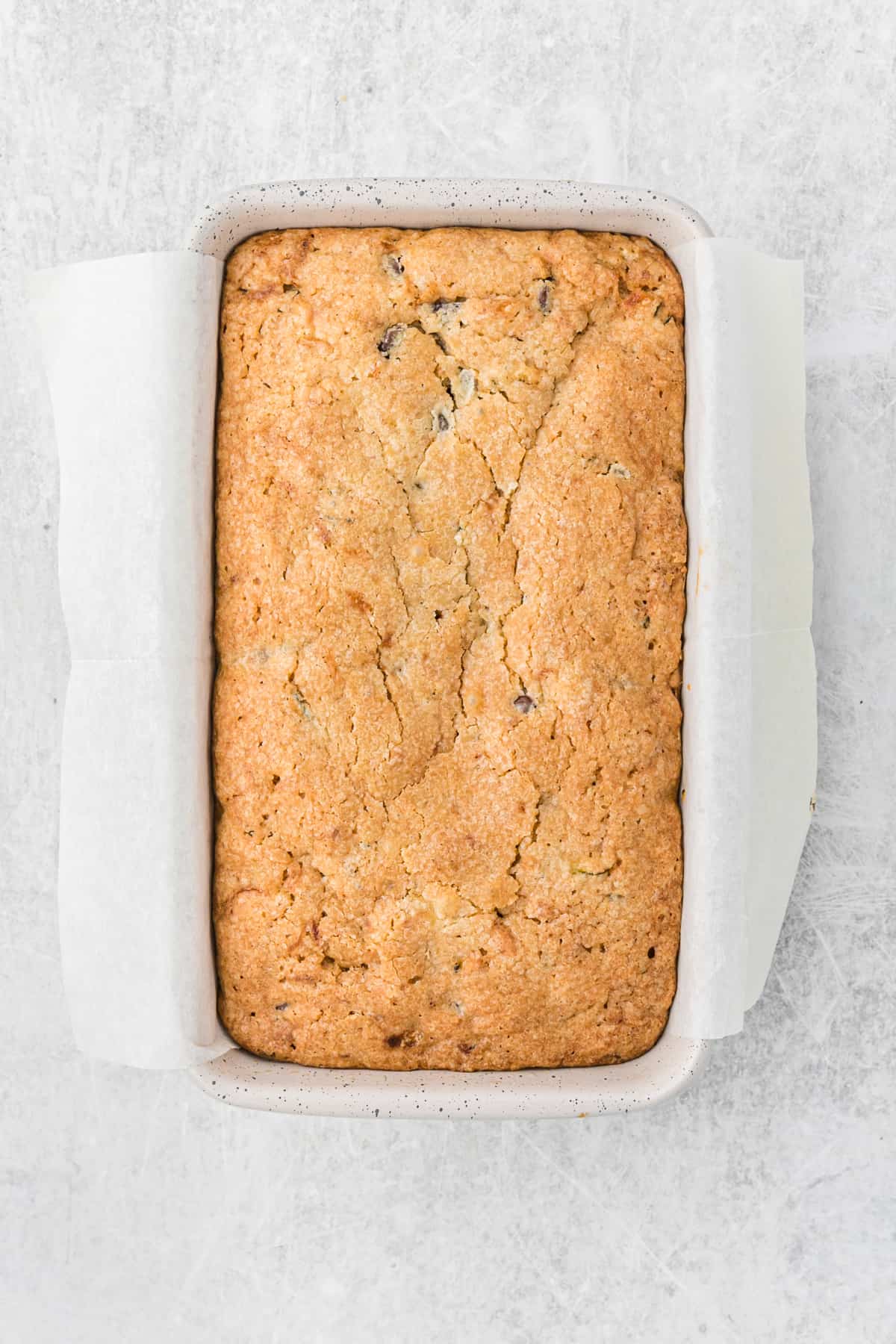 Baked loaf of chocolate chip zucchini bread in a loaf pan.