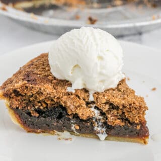 A scoop of vanilla ice cream on a slice of shoofly pie on a white plate.