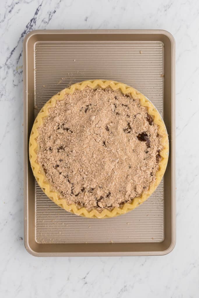 Assembled shoofly pie in a pie plate on a baking sheet ready to go in the oven.