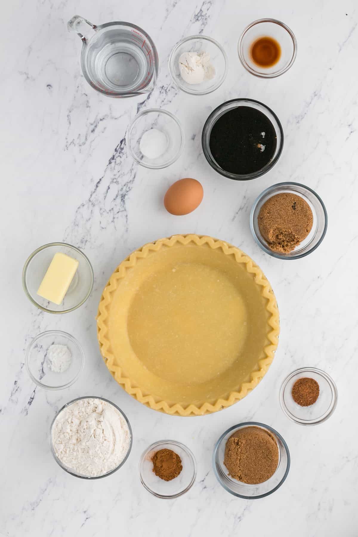 Ingredients to make a shoofly pie in small bowls on a white surface.