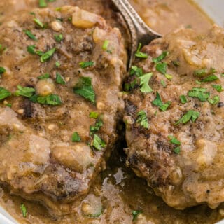 Round steak smothered in gravy in a white baking dish.