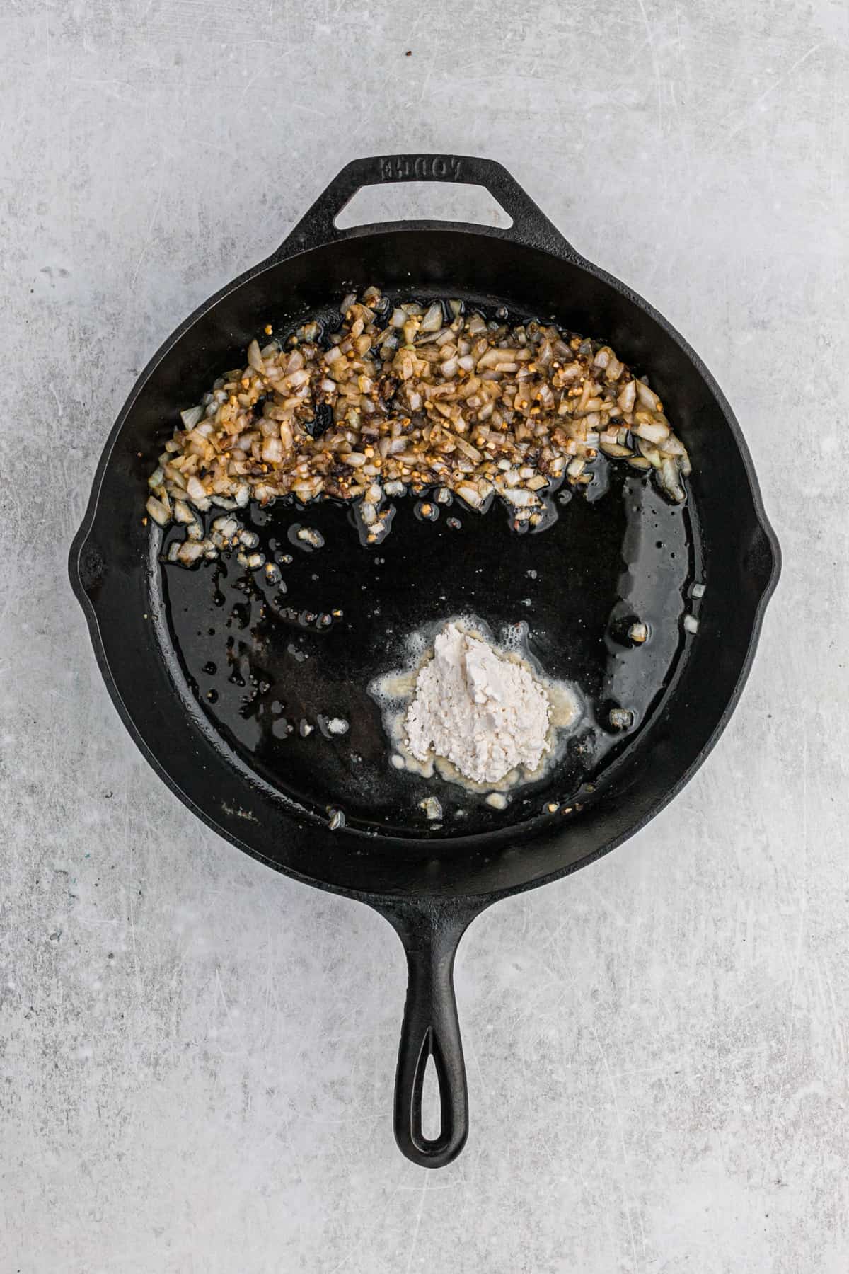 Onions and flour sautéing in fat in a cast iron skillet.