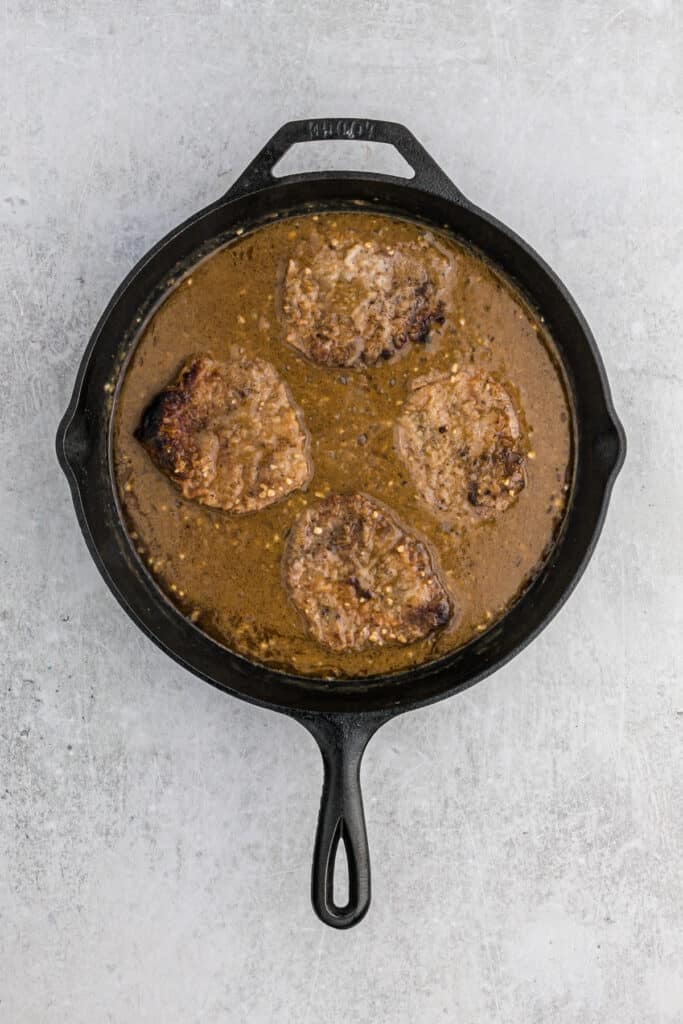 Round steak in onion gravy in a large cast iron skillet.