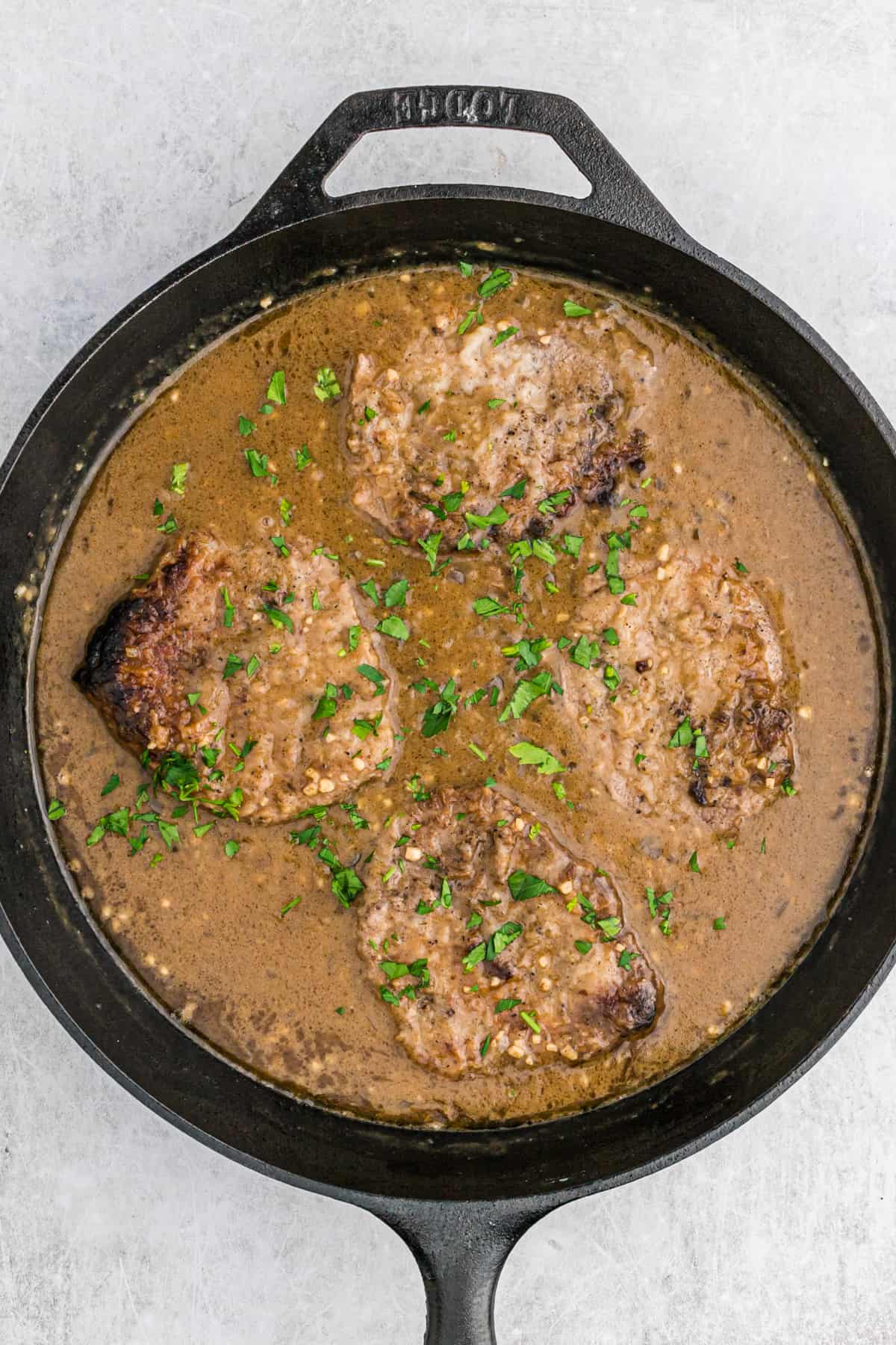 Round steak in onion gravy in a large cast iron skillet.