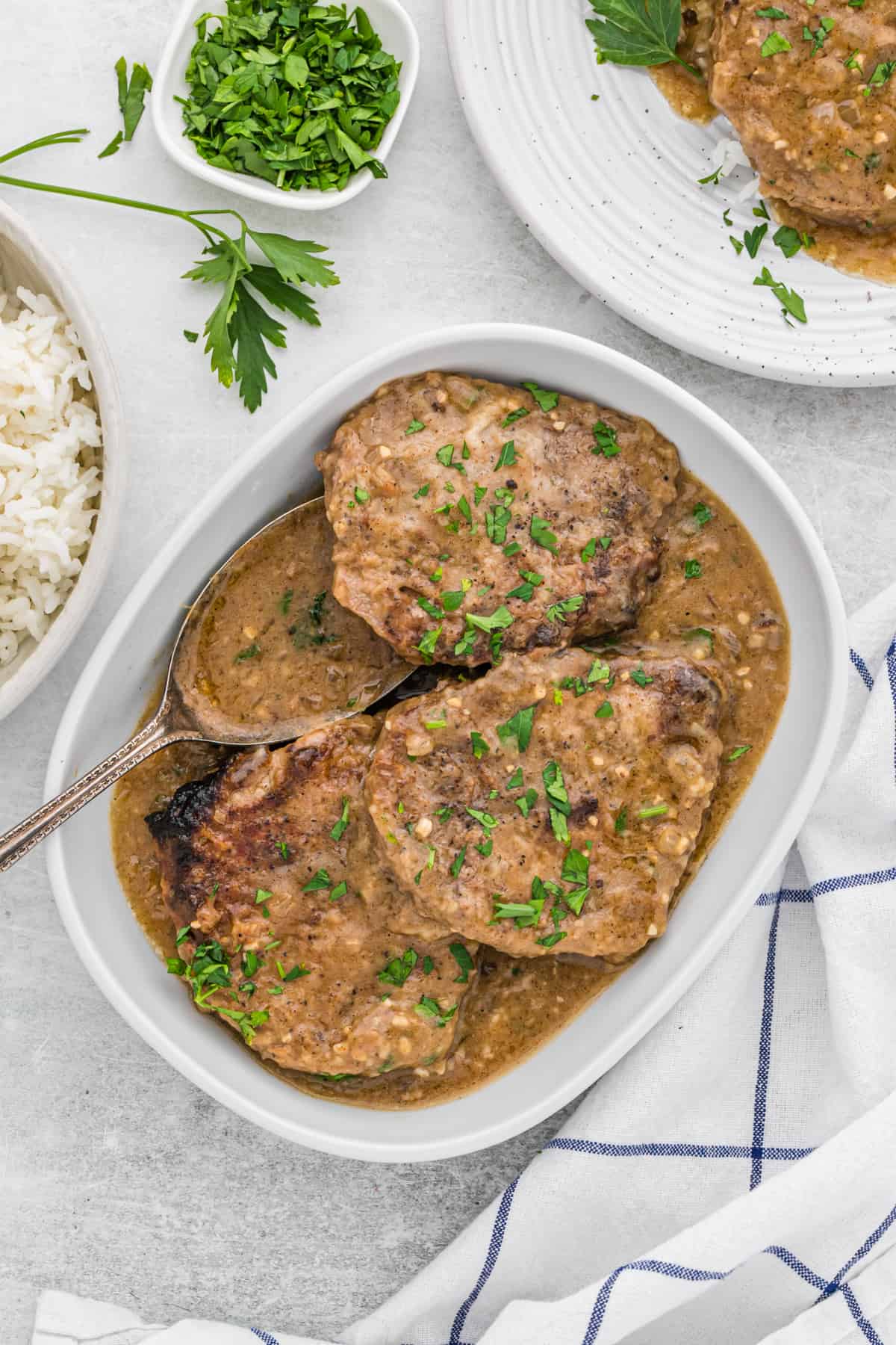 Round steak smothered in gravy in a white baking dish.