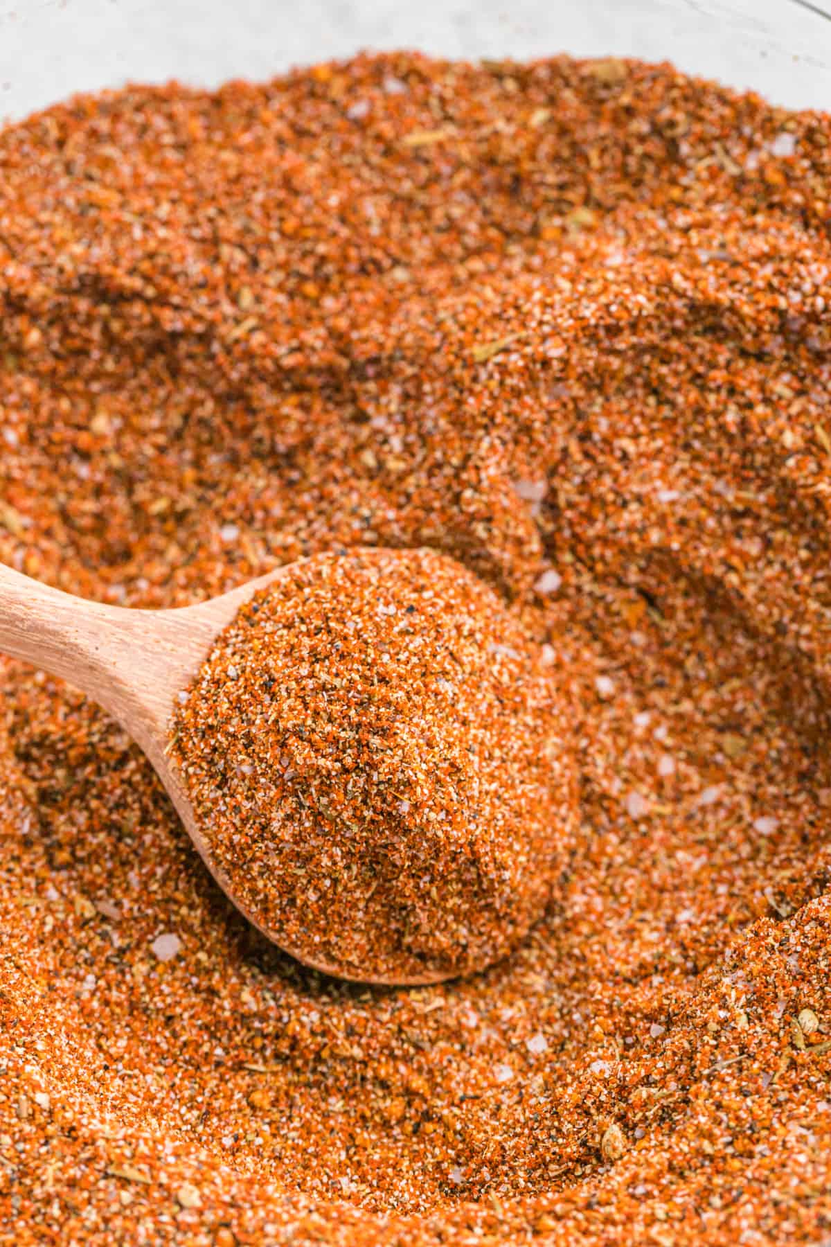 A wooden spoon in a mixing bowl of homemade turkey rub.