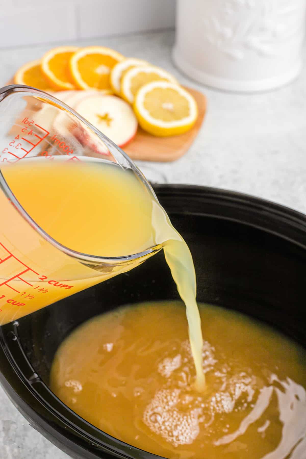 Juice being added to a crockpot to make wassail.