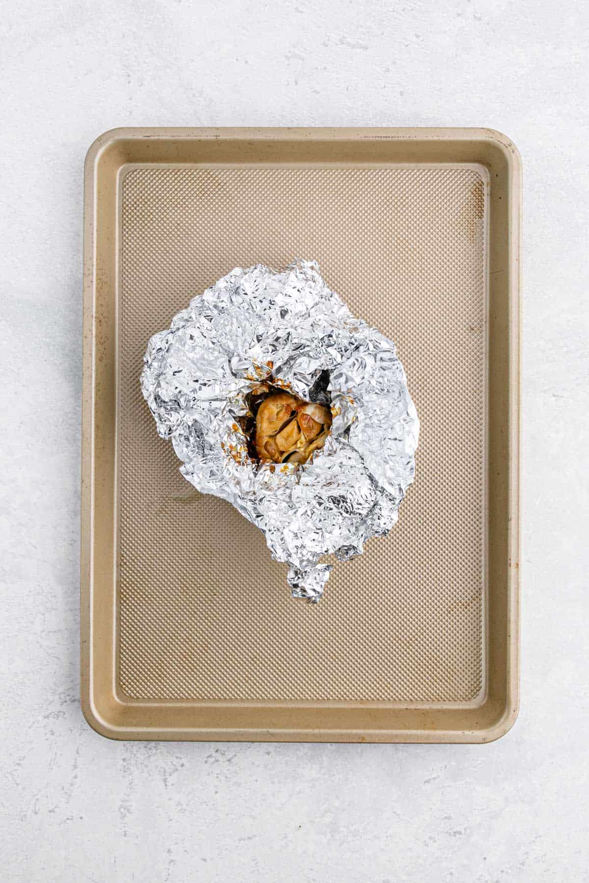 Roasted garlic in foil on a baking sheet