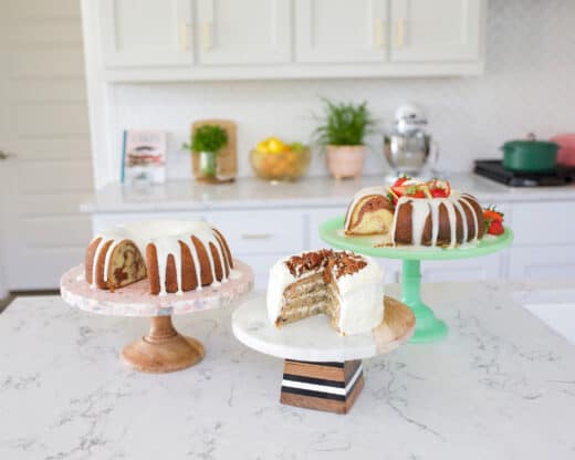 Three cakes on cake stands in a white kitchen