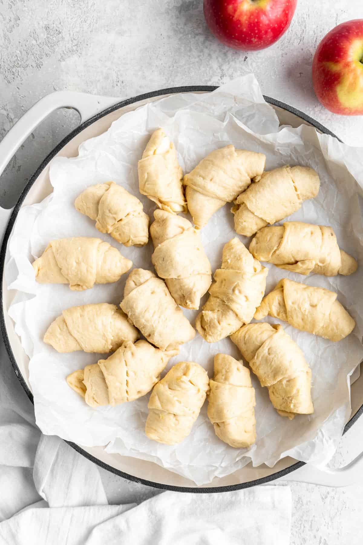 Apple dumplings wrapped up and put into a parchment lined pan