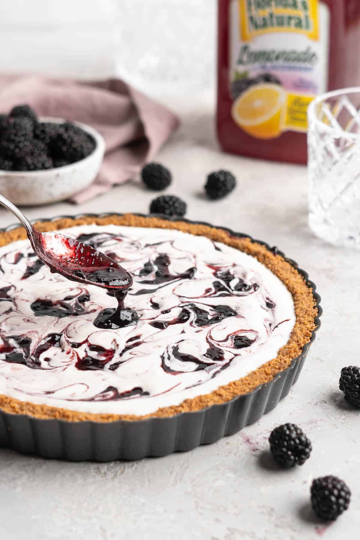 Blackberry jam being spooned over the top of a pie filling