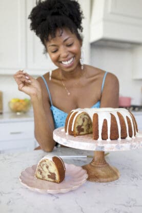 Jocelyn Delk Adams looking at a slice of Cinnamon Roll Pound Cake on a plate