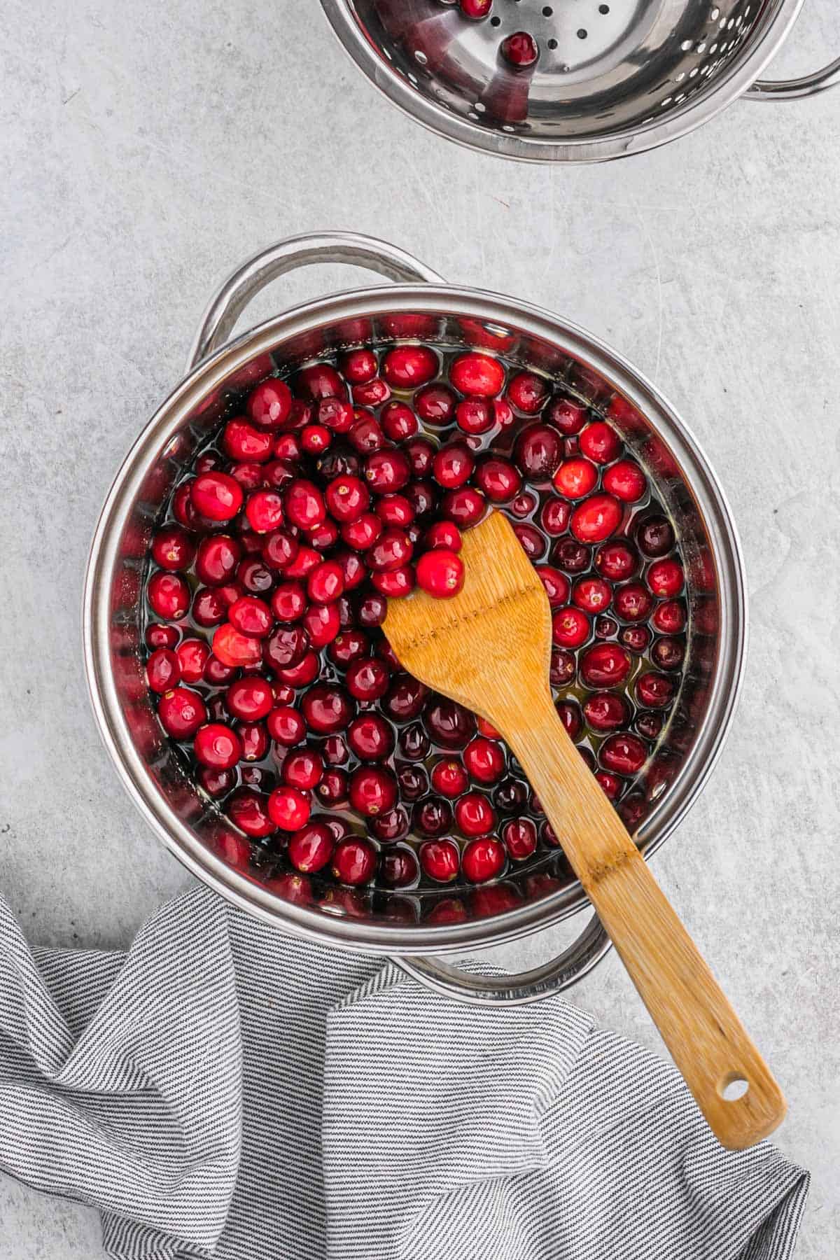 A wooden spatula in a pot of whole berry sauce.