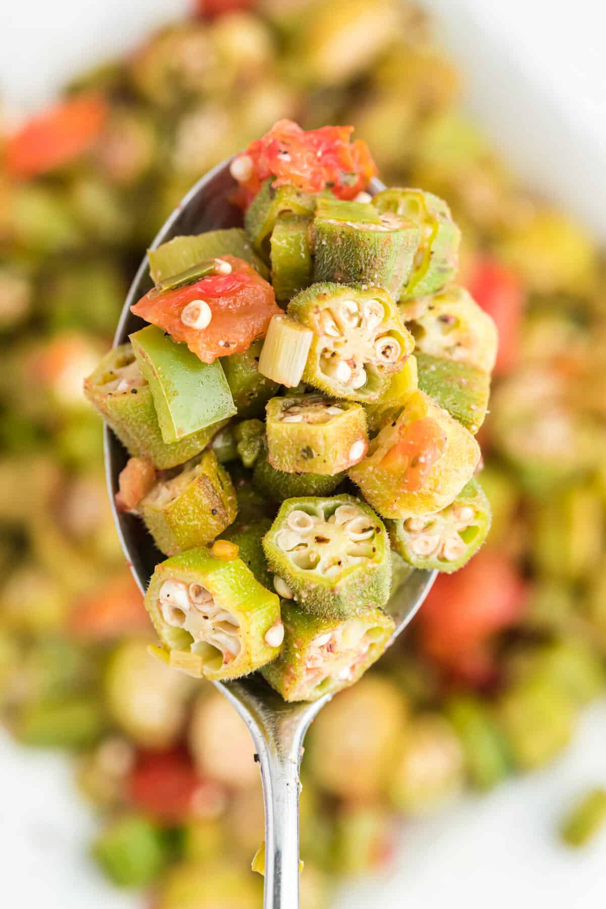 close up spoon full of okra and tomatoes