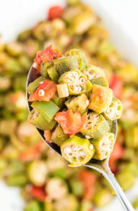 A close up of okra and tomatoes on a spoon