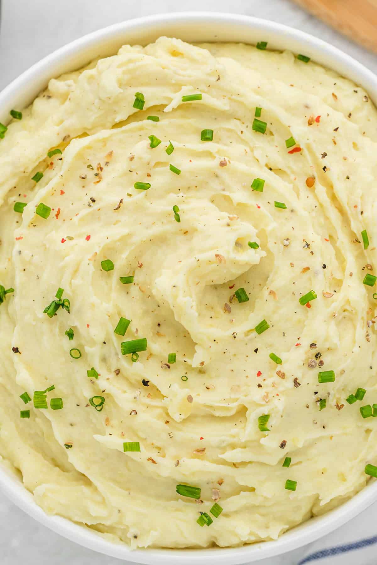 A close up of sour cream mashed potatoes recipe in a large white bowl ready to serve