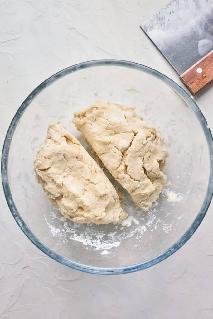 Pie dough cut in two sections inside of a glass bowl
