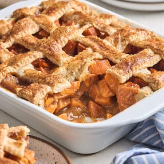 Rectangle baking dish of sweet potato cobbler with a corner slice removed.