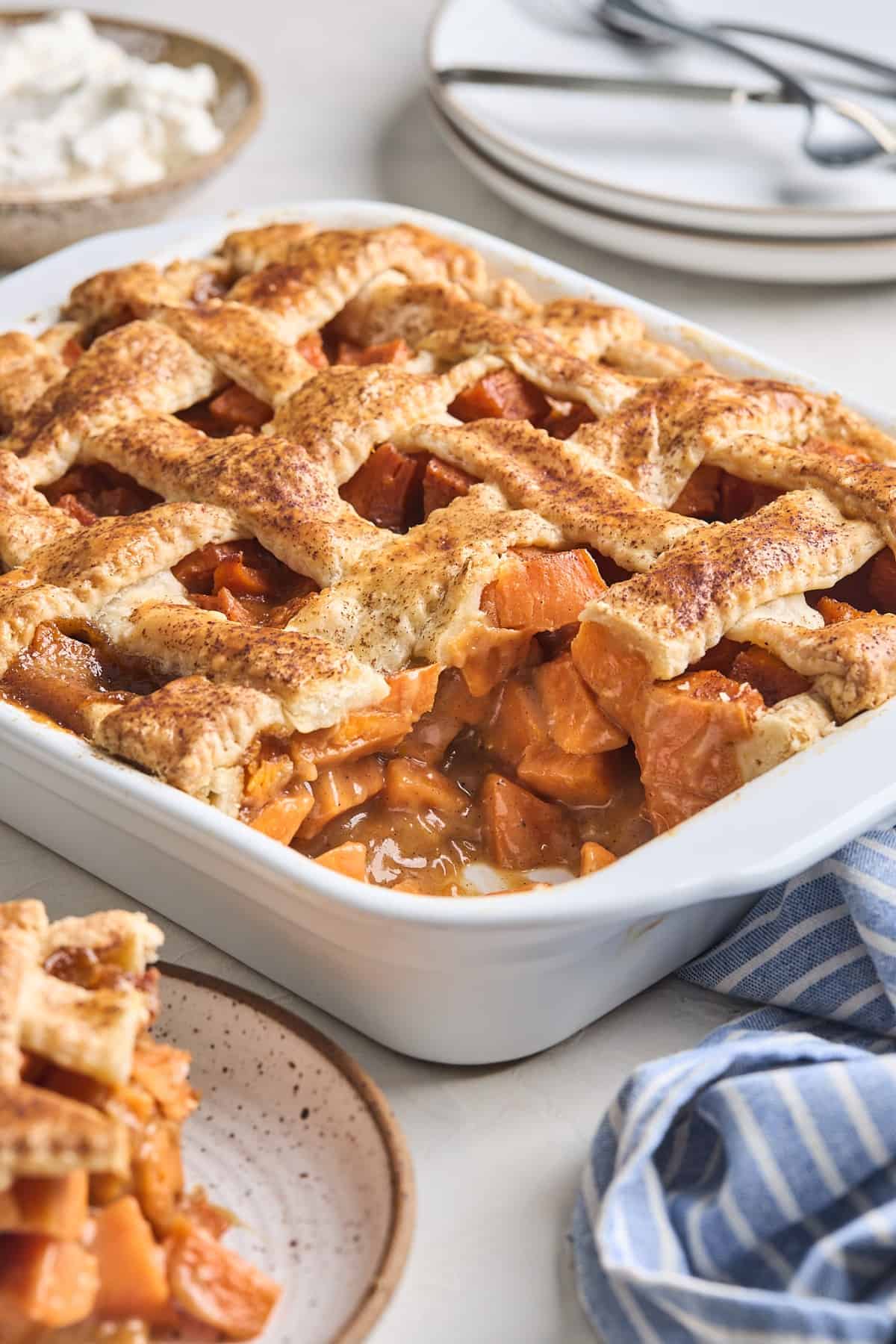 Rectangle baking dish of sweet potato cobbler with a corner slice removed.
