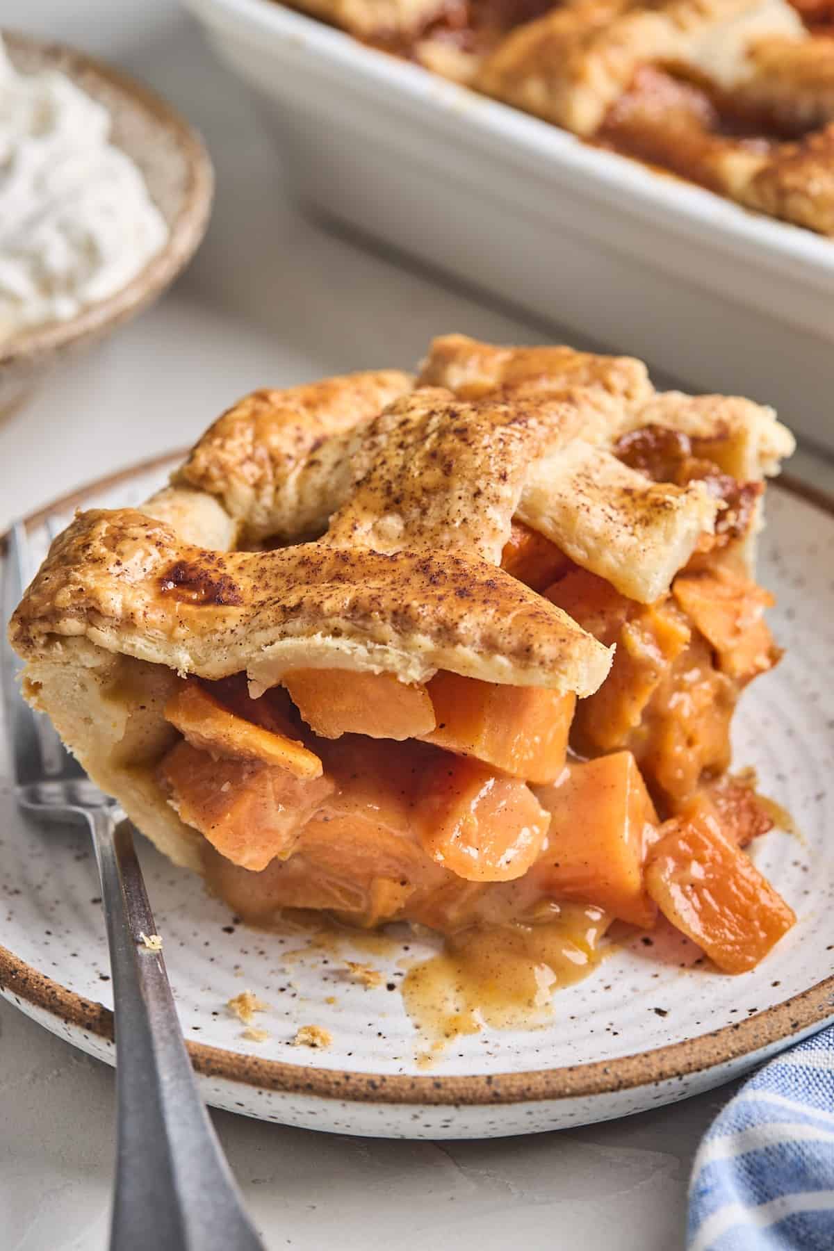 A slice of double crusted sweet potato cobbler recipe on a small stoneware plate.