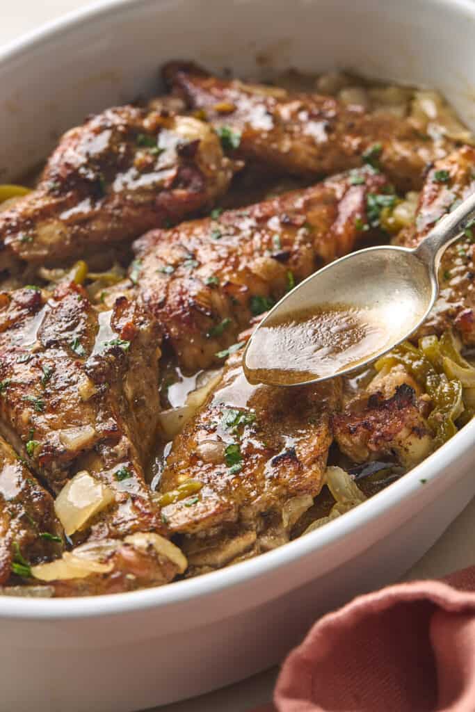 Turkey wings in a dish being basted with a spoon