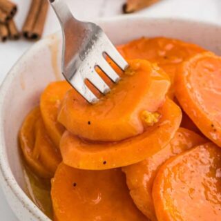 A fork in a bowl of sliced candied yams.