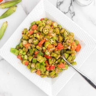 large white square dish filled with okra and tomatoes with a spoon