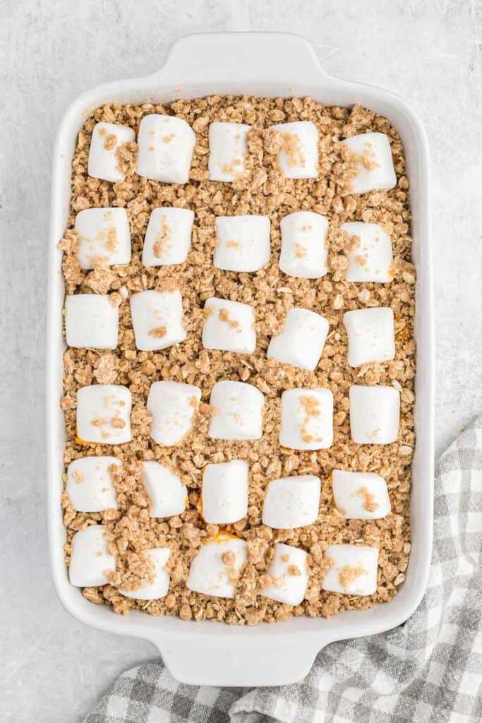 Adding the streusel topping to the top of sweet potato casserole.