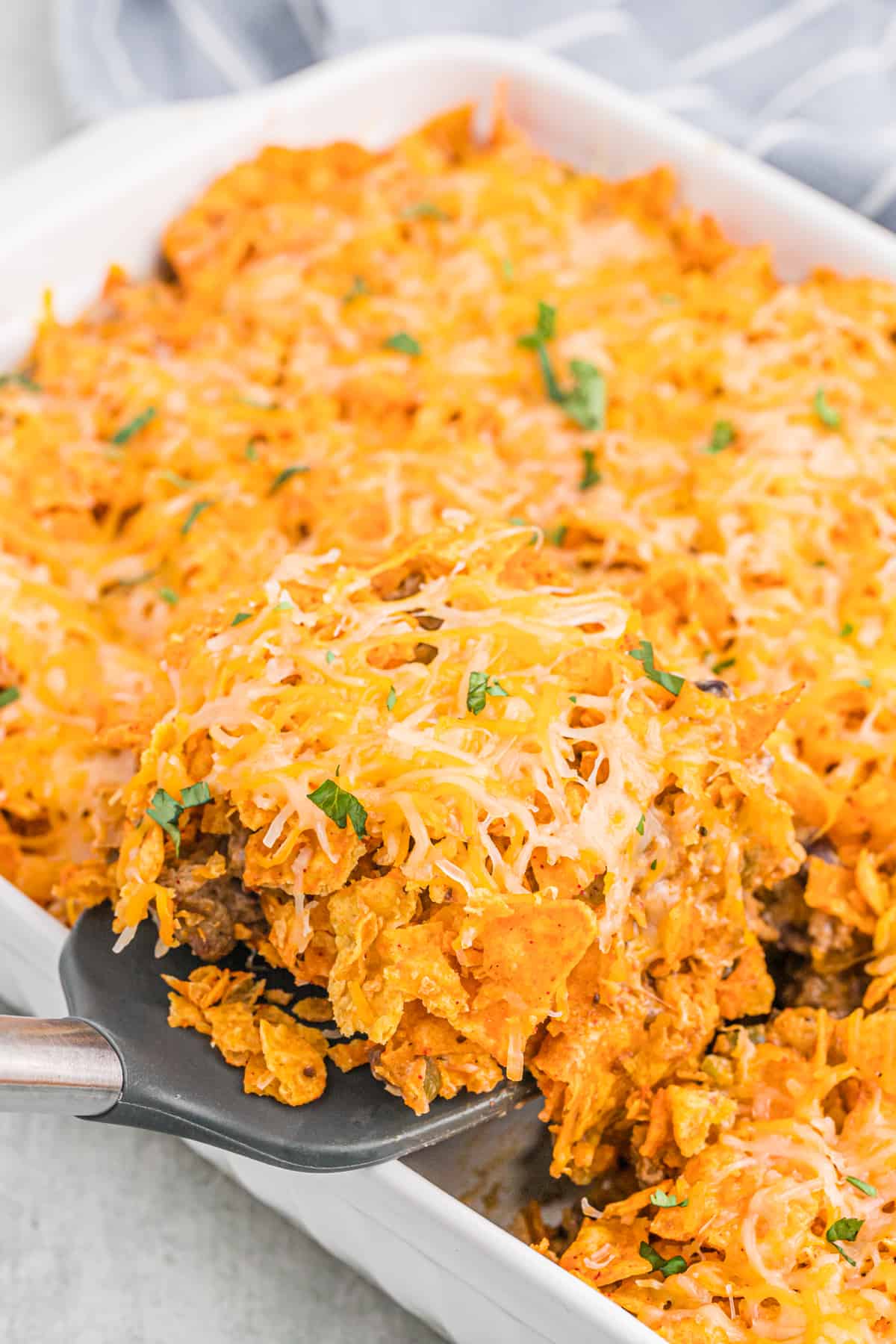 A close up of cheesy dorito pie being pulled from casserole