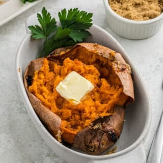 A large baked sweet potato in a white baking dish.