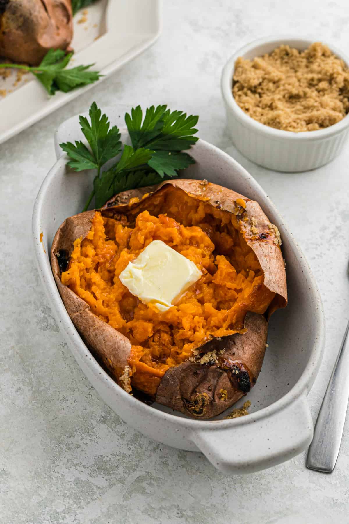 A large baked sweet potato in a white baking dish.