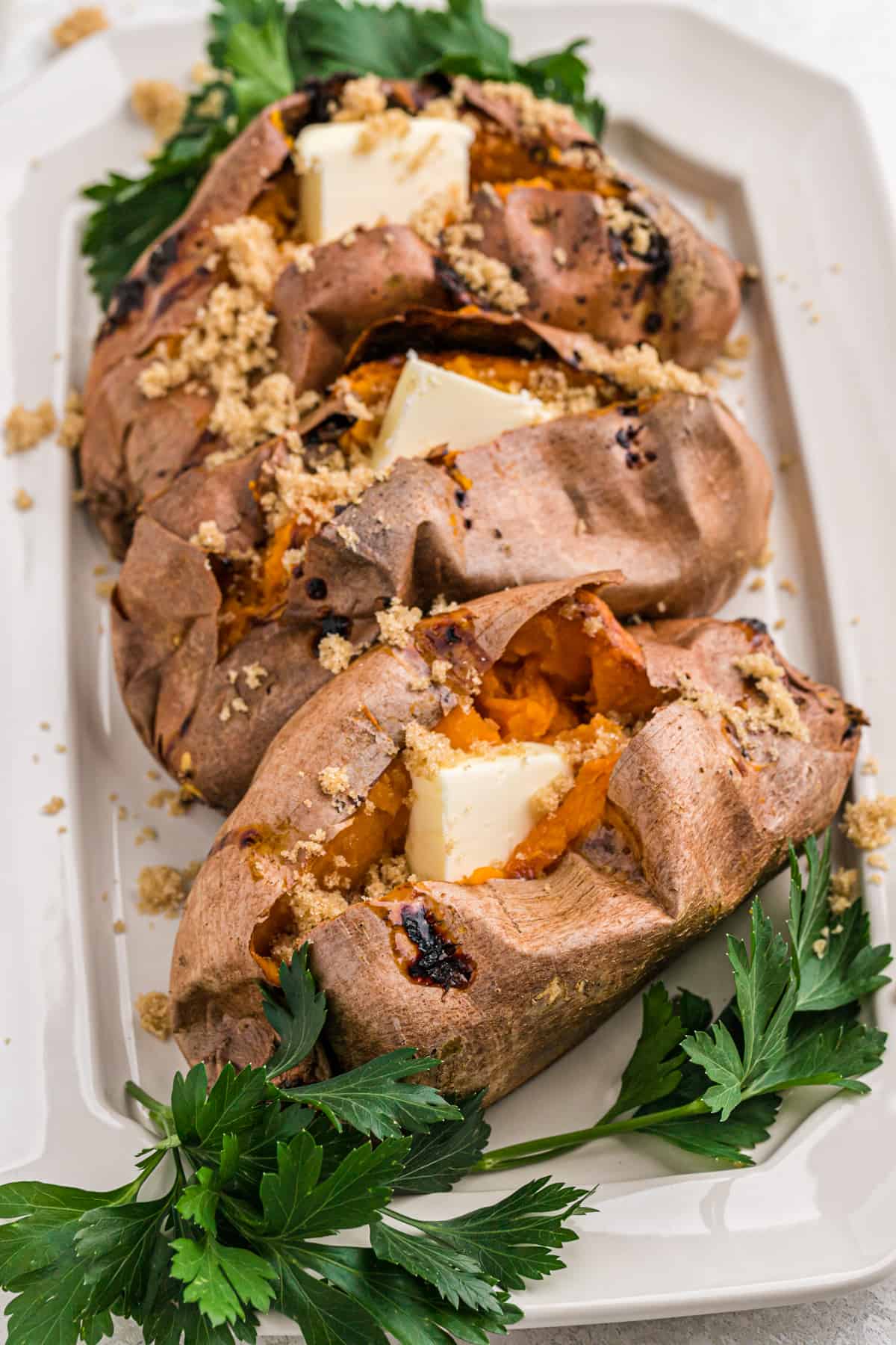 Baked sweet potatoes with butter on a serving platter.
