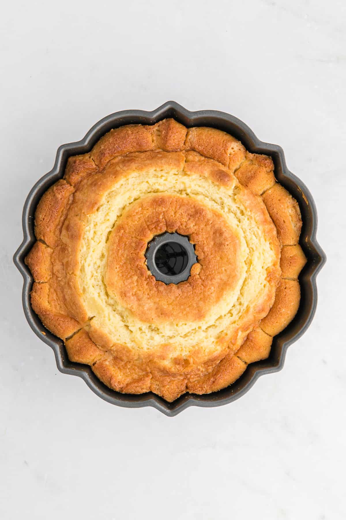 Baked sour cream pound cake recipe in a bundt pan on a white countertop