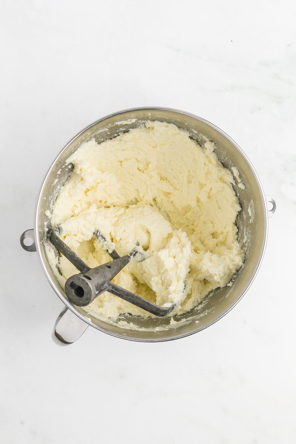 Butter and granulated sugar in a stand mixer bowl on white countertop