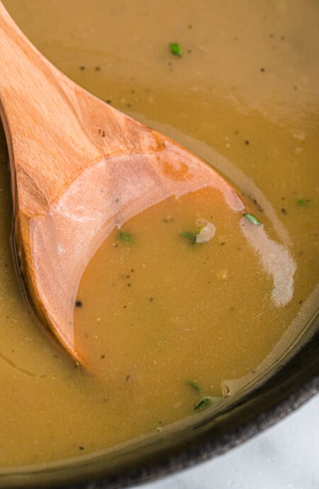 A wooden spoon in a saucepan of turkey gravy.