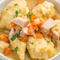 A delicious white bowl of turkey and dumplings ready to enjoy