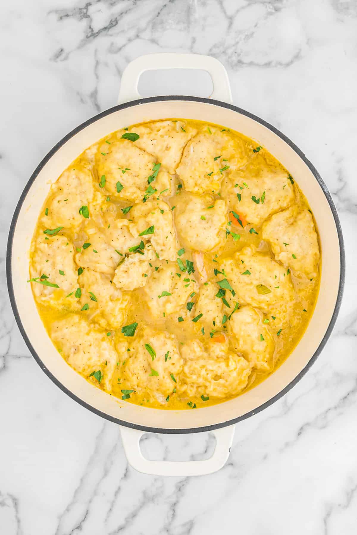 Completed turkey and dumplings in a large white pot on white countertop