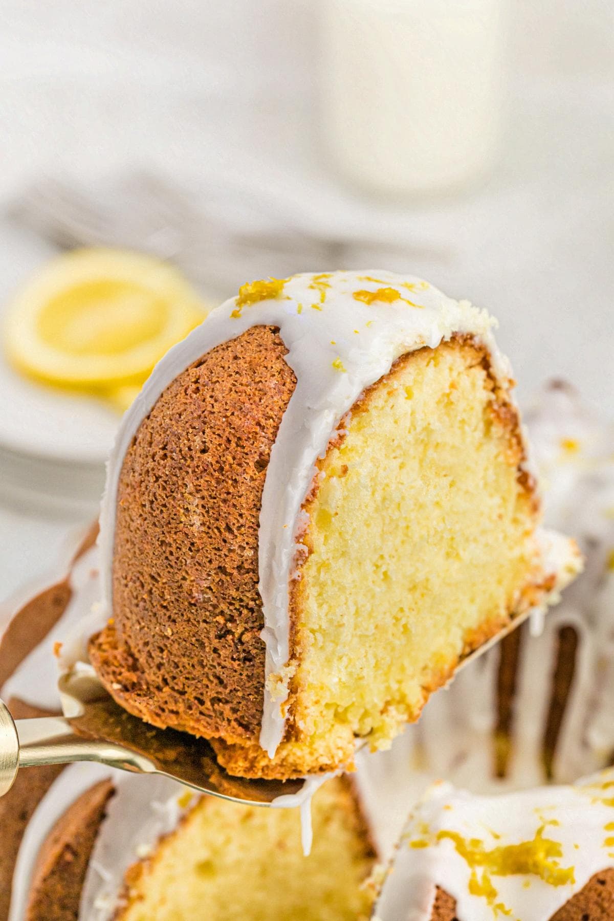 Slice of lemon pound cake on a cake spatula, showing a moist, tender crumb with lemon glaze