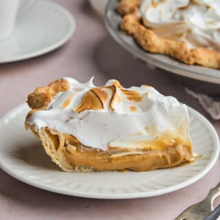 slice of butterscotch pie on a white plate with toasted meringue.
