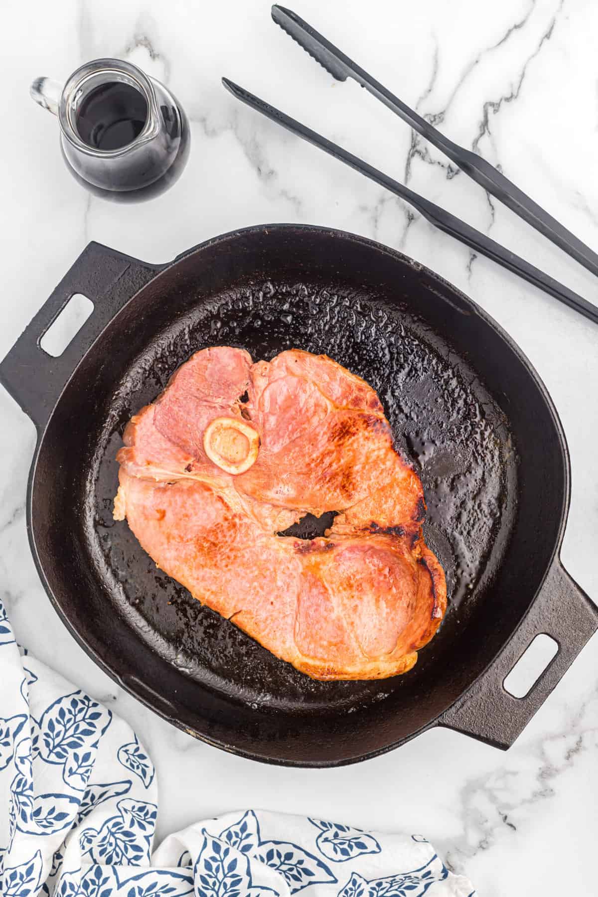 A ham steak searing in a cast iron skillet.