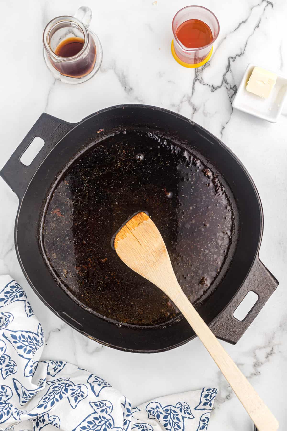 A wooden spoon scraping up all the good bits in a cast iron skillet.