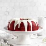 iced red velvet bundt cake on a cake pedestal
