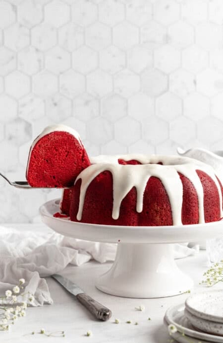 red velvet bundt cake on a cake pedestal with a slice taken out